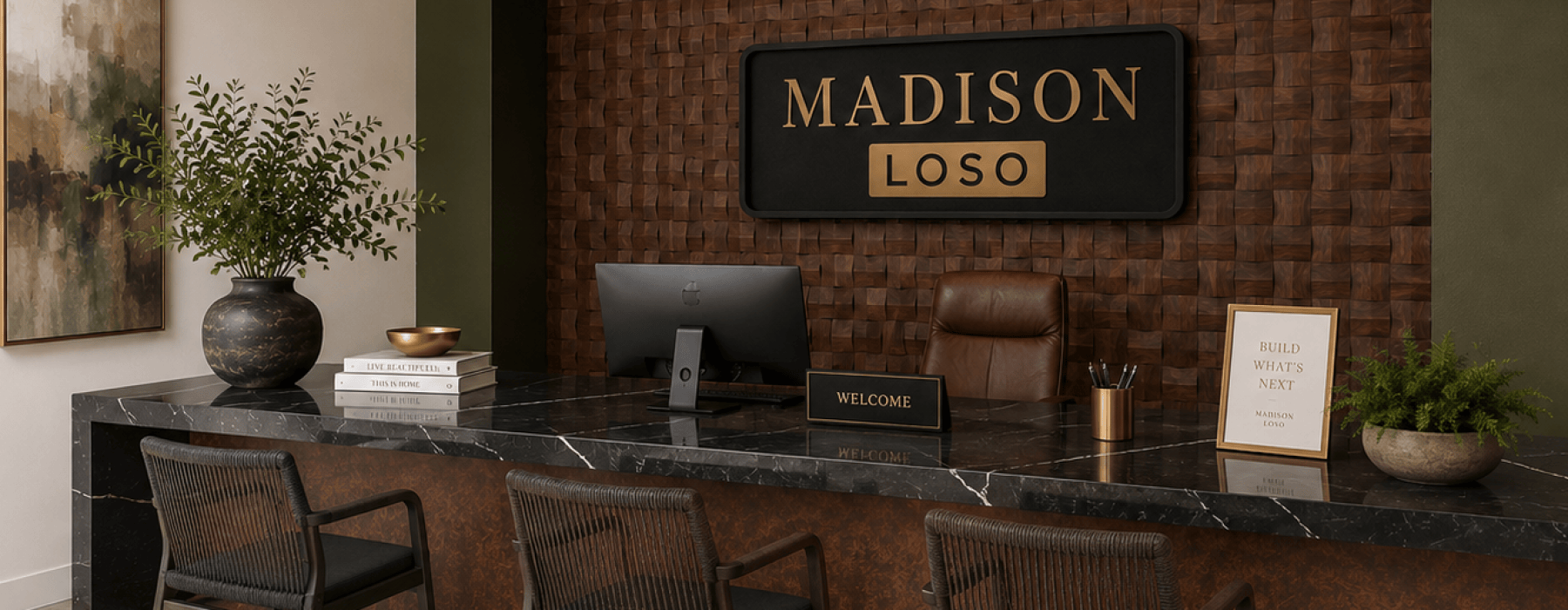 Leasing office interior at Madison apartments in LoSo Charlotte, NC featuring a modern marble reception desk, wood accent wall with gold “Garten” signage, hanging greenery, and a leasing agent assisting a prospective resident in a bright, upscale space.