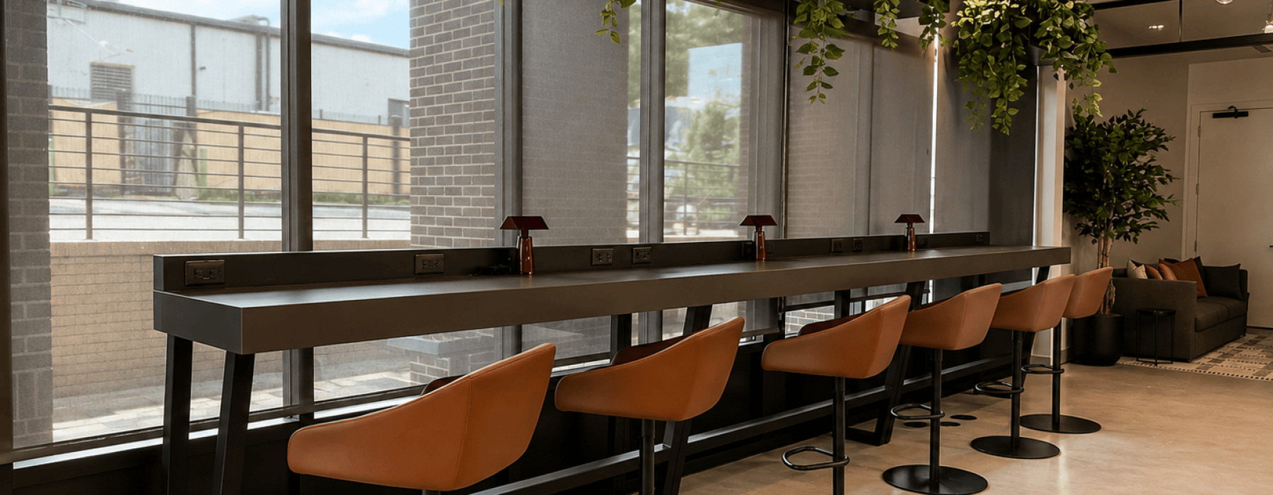 High-end apartment co-working space with built-in coffee bar, shared work tables, modern lighting, and indoor greenery at Garten apartments in LoSo Charlotte.